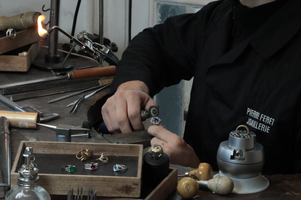 bijoutier à la cheville travaillant sur une bague saphir diamant